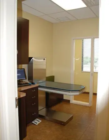 A room with a desk and laptop on the table