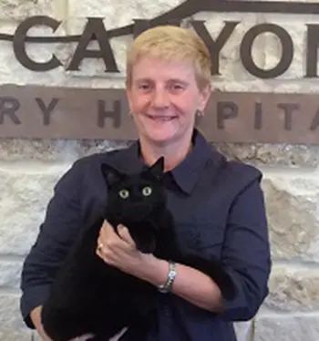 A woman holding a black cat in front of a building.