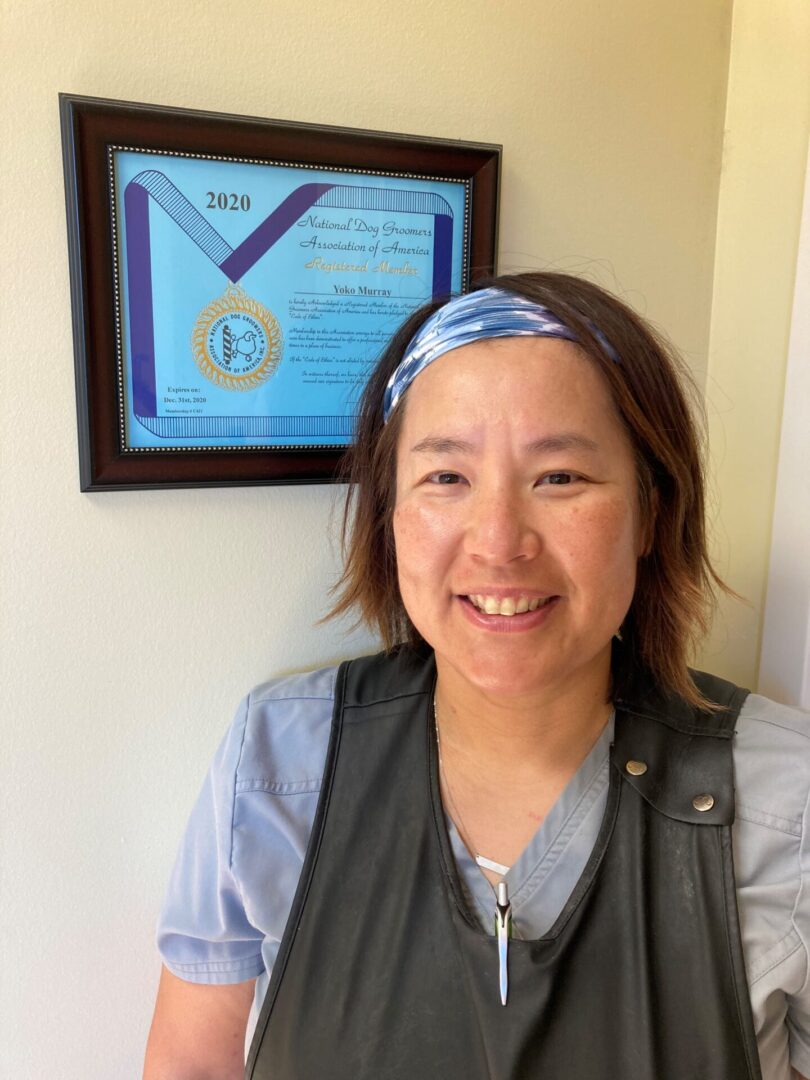 A woman with a blue headband standing in front of a framed certificate.