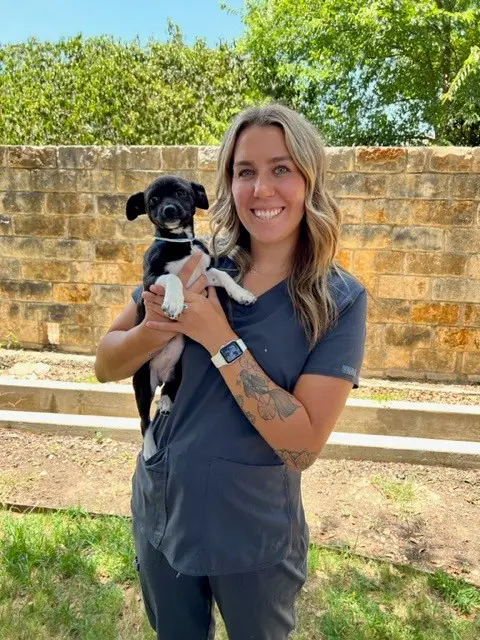 A woman holding a small dog in her arms.